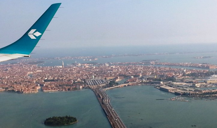 En känd kampanil ungefär i mitten av bilden. Bron och flygbolaget ger andra tips. Liksom det helt uppenbara i bilden...